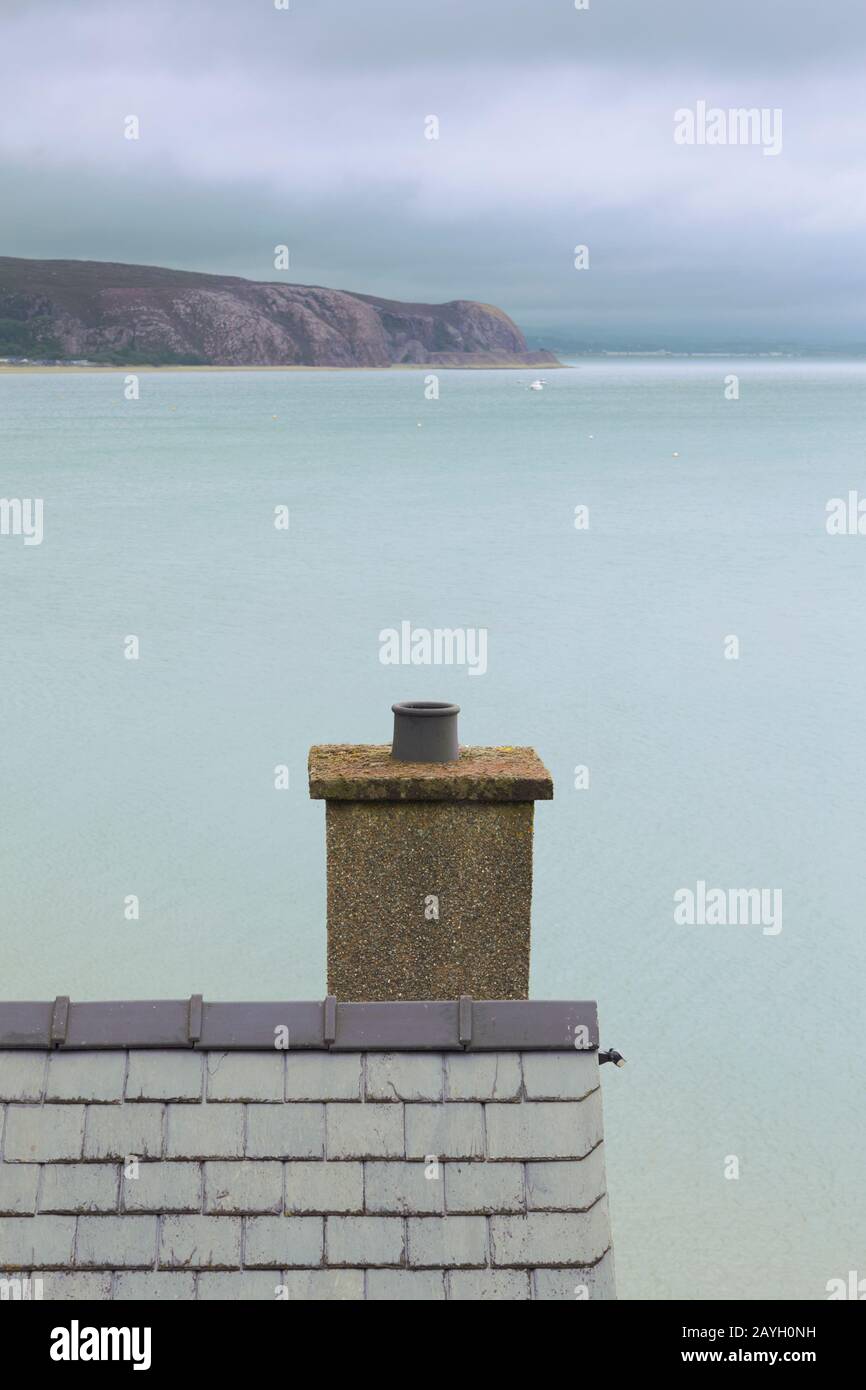 Vista elevata del tetto in ardesia gallese e camino con mare e punta sullo sfondo a Abersoch sulla costa nord del galles uk Foto Stock