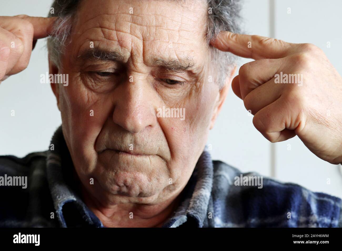 L'uomo anziano massaggia i templi con le mani. Ritratto di pensiero maschile su qualcosa, concetto di attività mentale in età avanzata, memoria, mal di testa Foto Stock