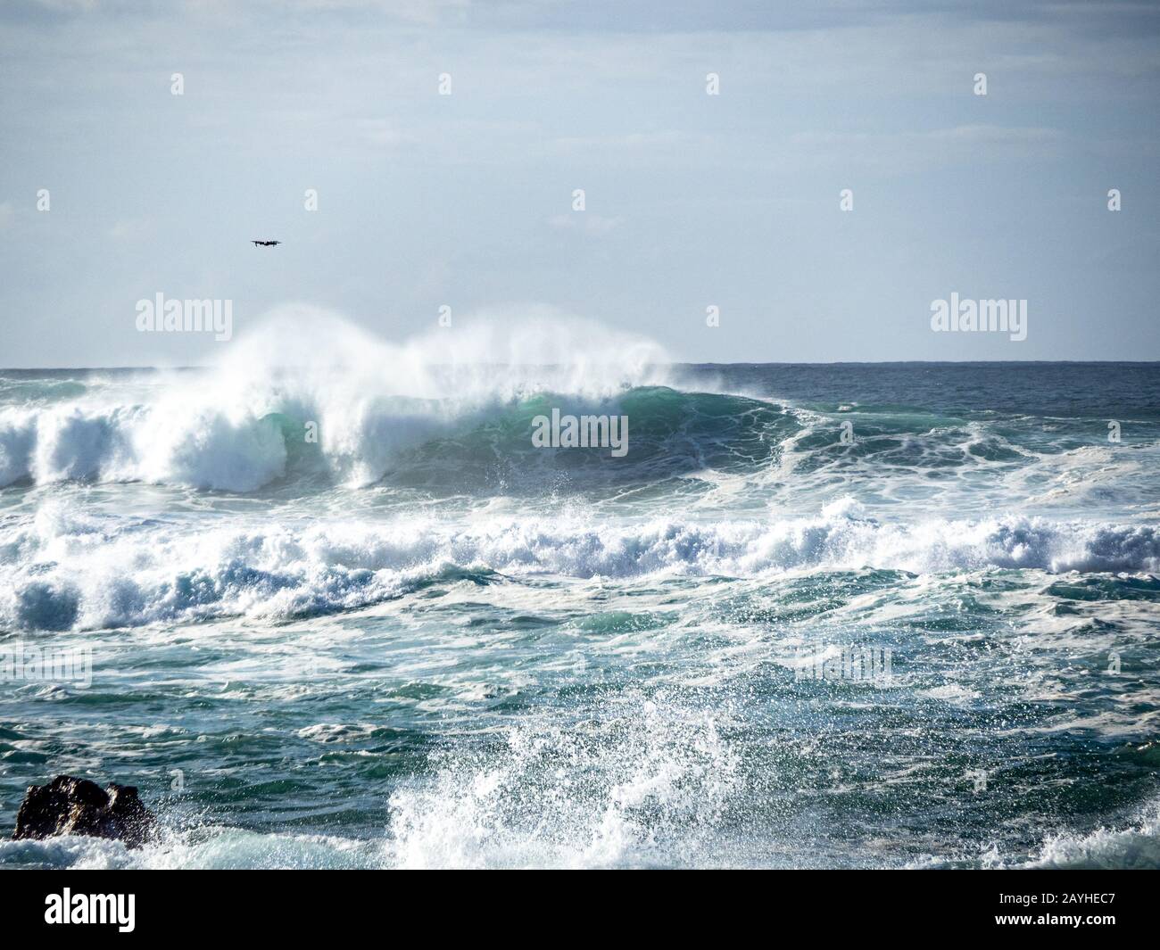 Grandi onde sulla costa settentrionale di Oahu con mare acquamarina, schiuma bianca e cieli blu. Drone volo overhead tenta di catturare surfisti. Foto Stock