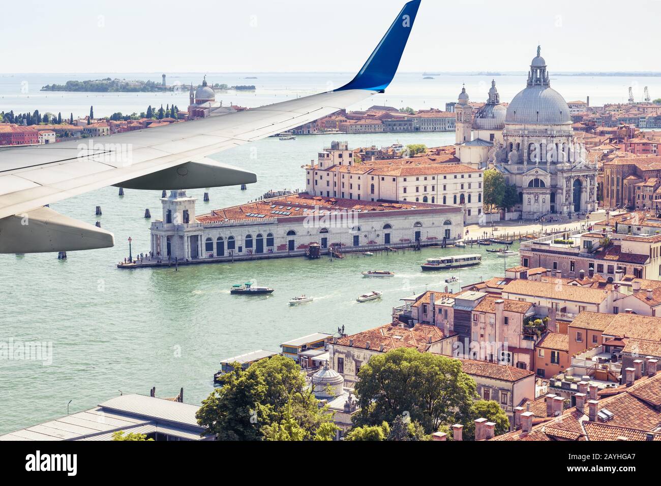 L'aereo vola sopra Venezia, Italia. Vista panoramica aerea della città e del mare dalla finestra dell'aereo. L'ala dell'aereo sopra Venezia durante il decollo o l'atterraggio Foto Stock