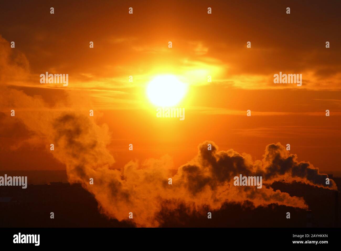 Sole rosso al tramonto o all'alba al tramonto, sotto l'orizzonte, avvolto  nel fumo dai camini della pianta Foto stock - Alamy
