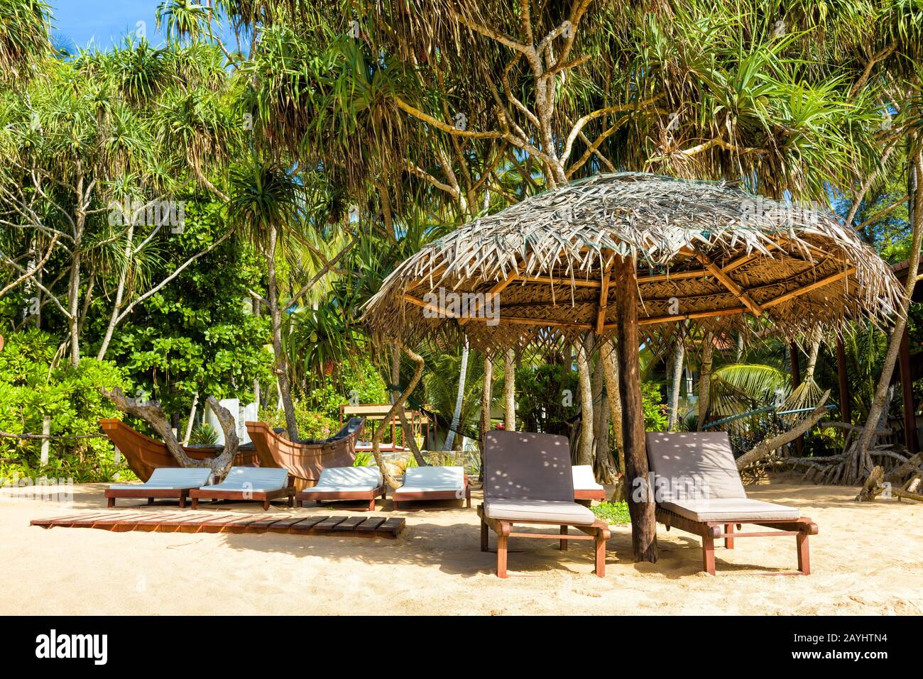 Tangalle, Sri Lanka - 4 novembre 2017: Spiaggia tropicale con ombrelloni e lettini. Rilassatevi sulla soleggiata spiaggia del resort. Hotel tra palme. Viaggio destin Foto Stock