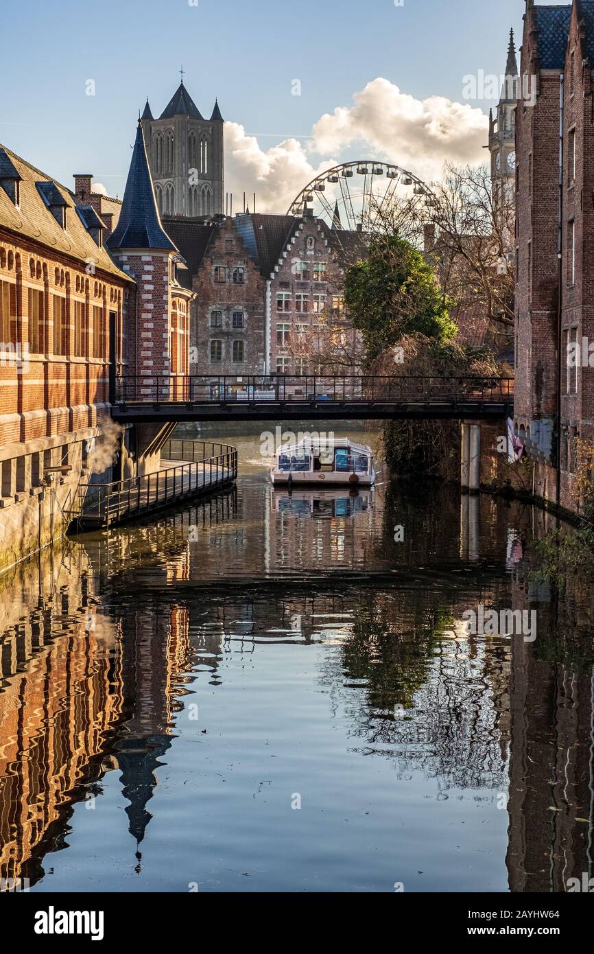 Un battello fluviale sul canale di Gand con una ruota ferris e la Chiesa di San Nicola sullo sfondo Foto Stock