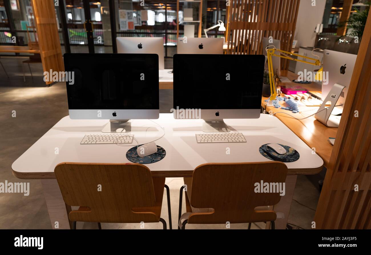 Moderna postazione di lavoro per ufficio con computer Apple iMac su un tavolo bianco in legno - spazio creativo e lavoro Foto Stock