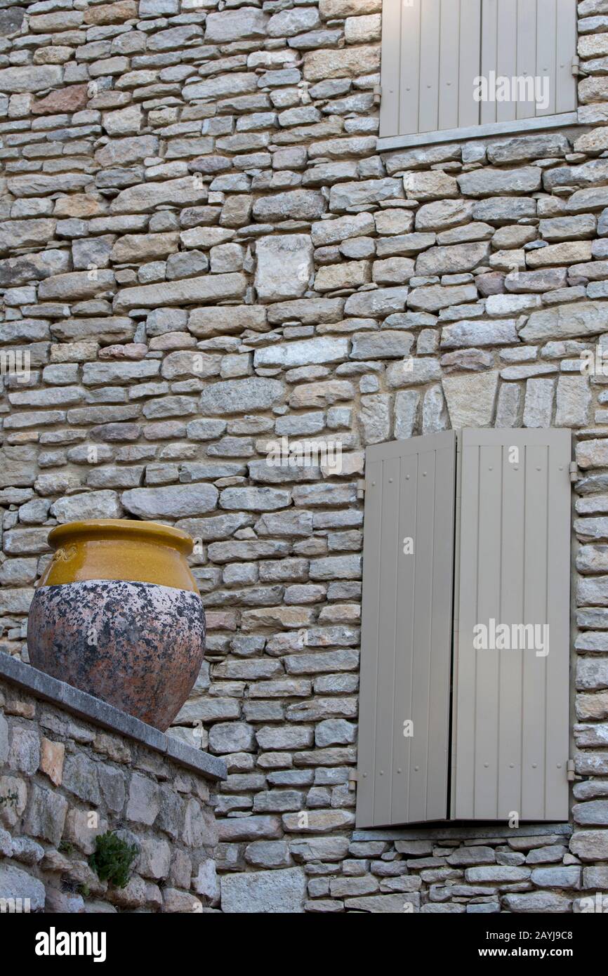 Una scena di villaggio con un vaso di ceramica su un muro di fronte a una casa di pietra nel borgo medievale di Goult nel Luberon, Provenza-Alpi-Costa Azzurra reg Foto Stock