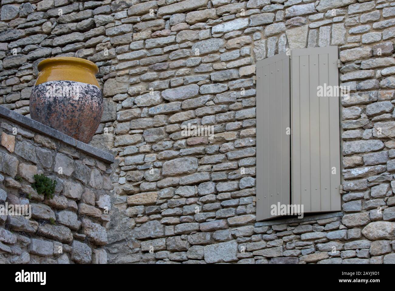 Una scena di villaggio con un vaso di ceramica su un muro di fronte a una casa di pietra nel borgo medievale di Goult nel Luberon, Provenza-Alpi-Costa Azzurra reg Foto Stock