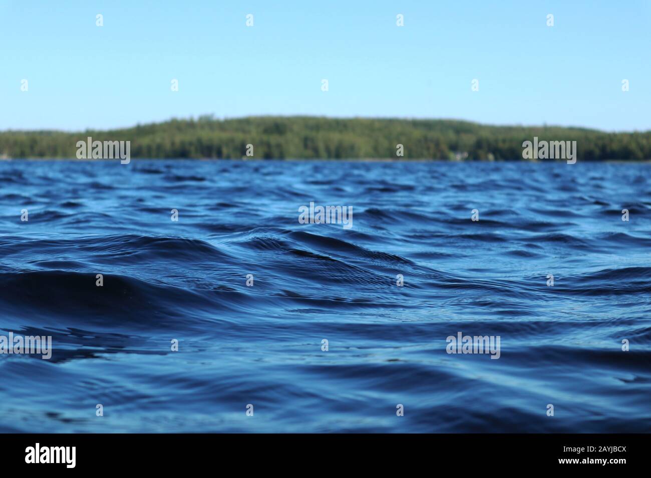 Blu acqua cielo chiaro giornata di sole sul lago finlandese onde d'acqua chiudere. Bellezza dello skyline della natura e della foresta con acqua dai colori profondi. Foto dalla barca Foto Stock