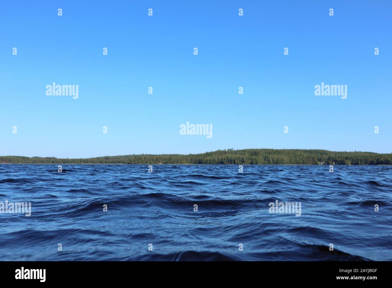 Blu acqua cielo chiaro giornata di sole sul lago finlandese onde d'acqua chiudere. Bellezza dello skyline della natura e della foresta con acqua dai colori profondi. Foto dalla barca Foto Stock