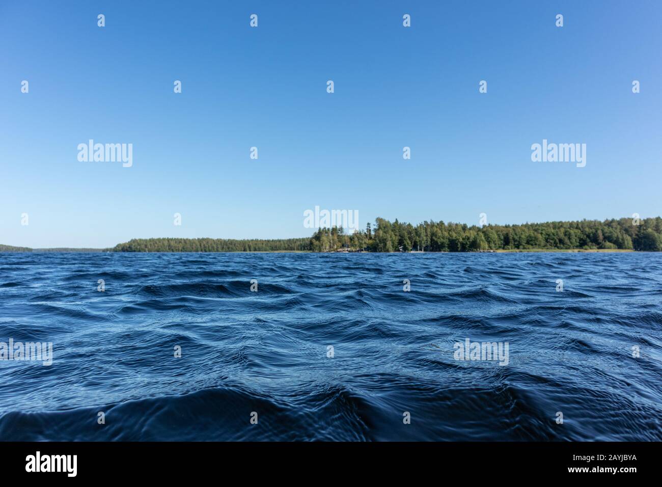 Blu acqua cielo chiaro giornata di sole sul lago finlandese onde d'acqua chiudere. Bellezza dello skyline della natura e della foresta con acqua dai colori profondi. Foto dalla barca Foto Stock