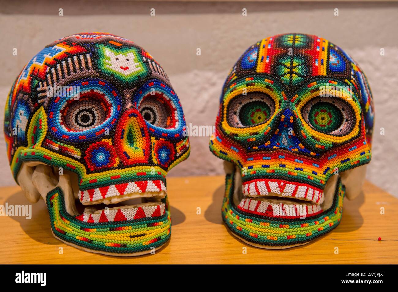 Teschi ricoperti di perle di vetro in mostra in una galleria d'arte a Oaxaca City, Messico. Foto Stock