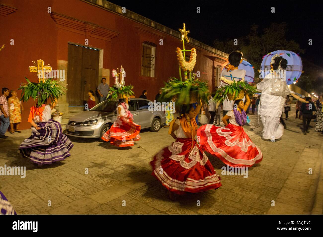 Donne vestite con un costume regionale e marionette giganti vestite da sposa e sposo durante una calenda, una processione per le strade del centro di Oaxa Foto Stock