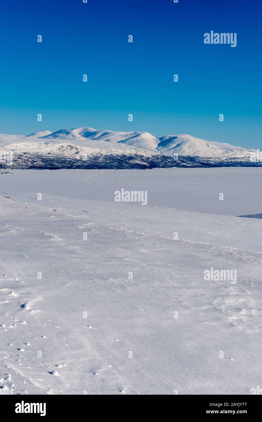 Paesaggio invernale con vista sul lago ghiacciato e innevato Tornetrak dalla strada per la stazione di Laktatjakko Mountain sopra la stazione sciistica di Bjorkliden i Foto Stock