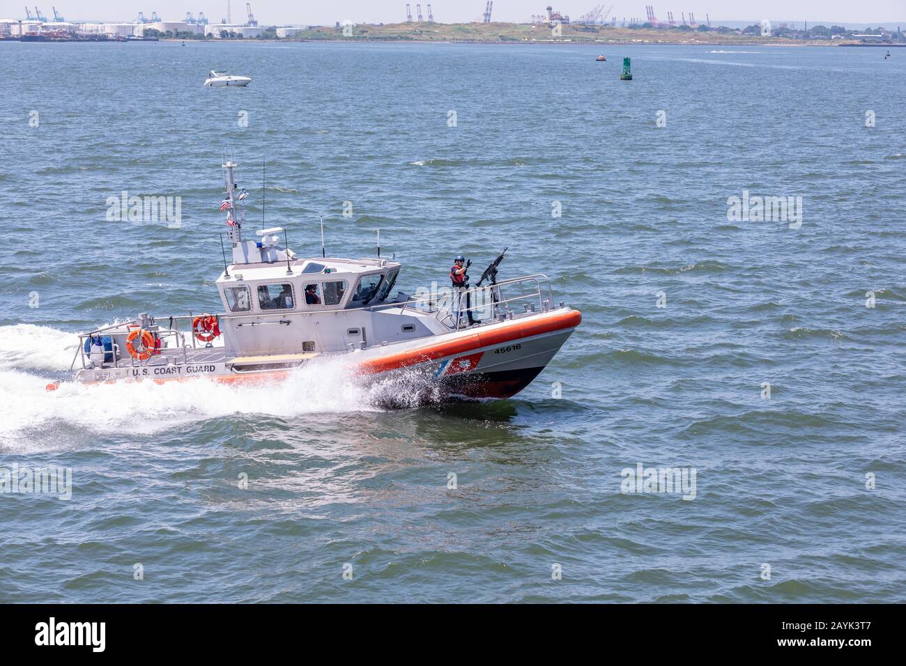 New York, NY USA - 30 giugno 2018: Pattugliano una barca della Guardia Costiera degli Stati Uniti nel porto di New York presso la Statua della libertà. Un ufficiale armato ondeggia la sua mano Foto Stock