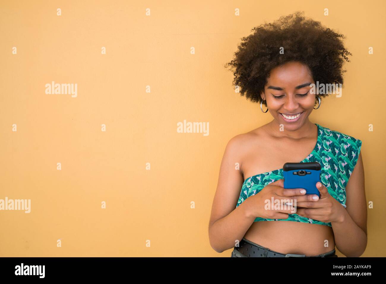 Ritratto di giovane afro americano latino donna utilizzando il suo cellulare e l'invio di messaggi. Concetto di tecnologia. Foto Stock