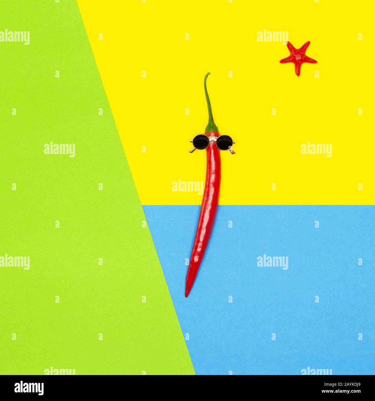 Peperoncino rosso in occhiali da sole con pesce stella come il sole su sfondo giallo, blu, verde. Estate spiaggia vacanze creativo concetto minimo Foto Stock