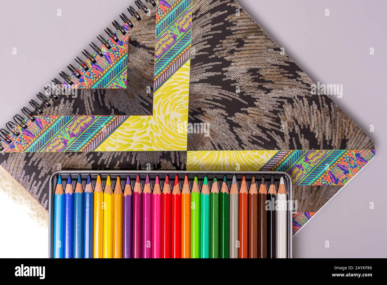 Una scatola con matite multicolore affilate si trova su uno sketchbook. Elementi per la creatività. Foto Stock