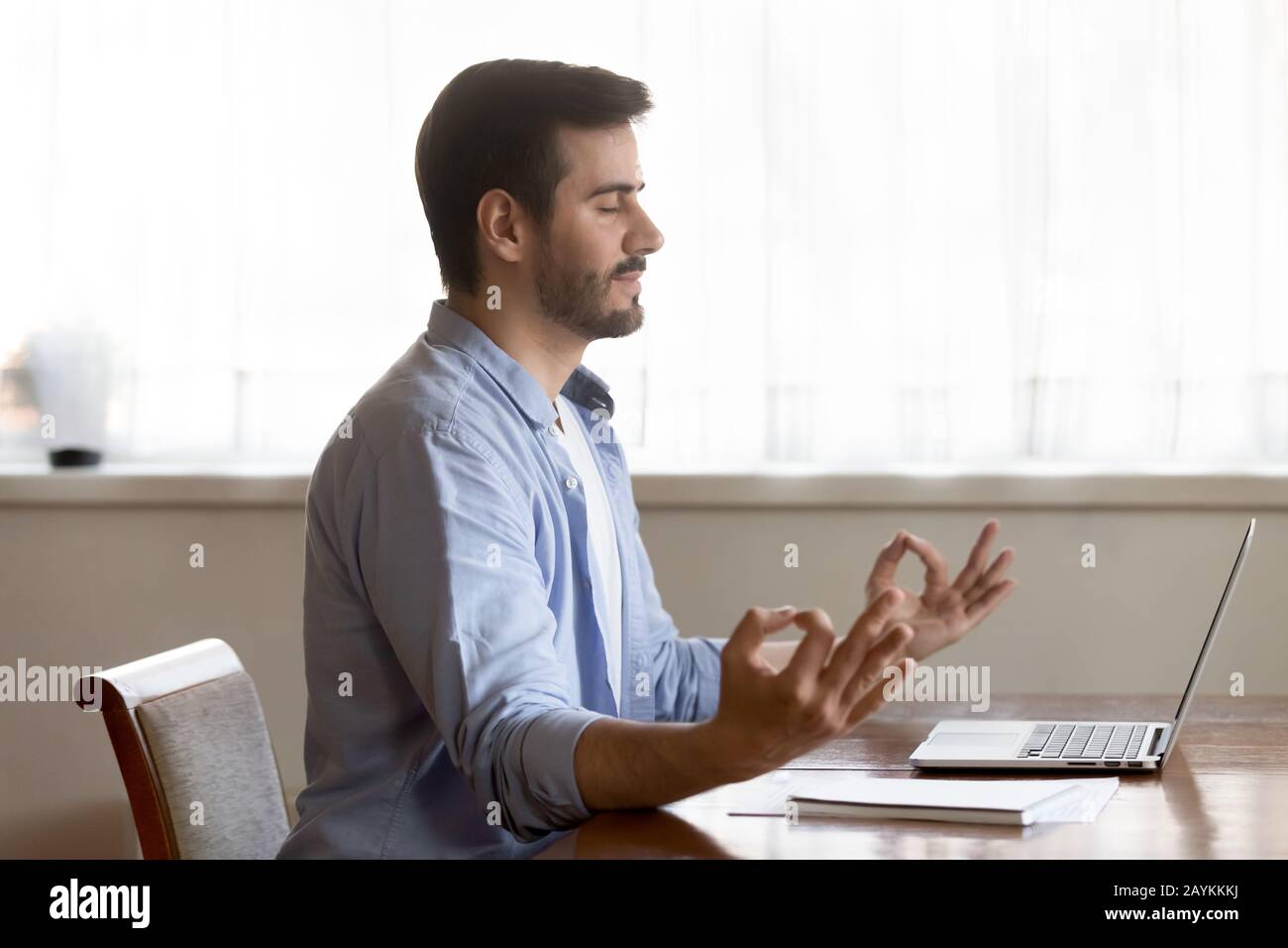 Pratica di yoga maschile concentrata meditando sul posto di lavoro Foto Stock