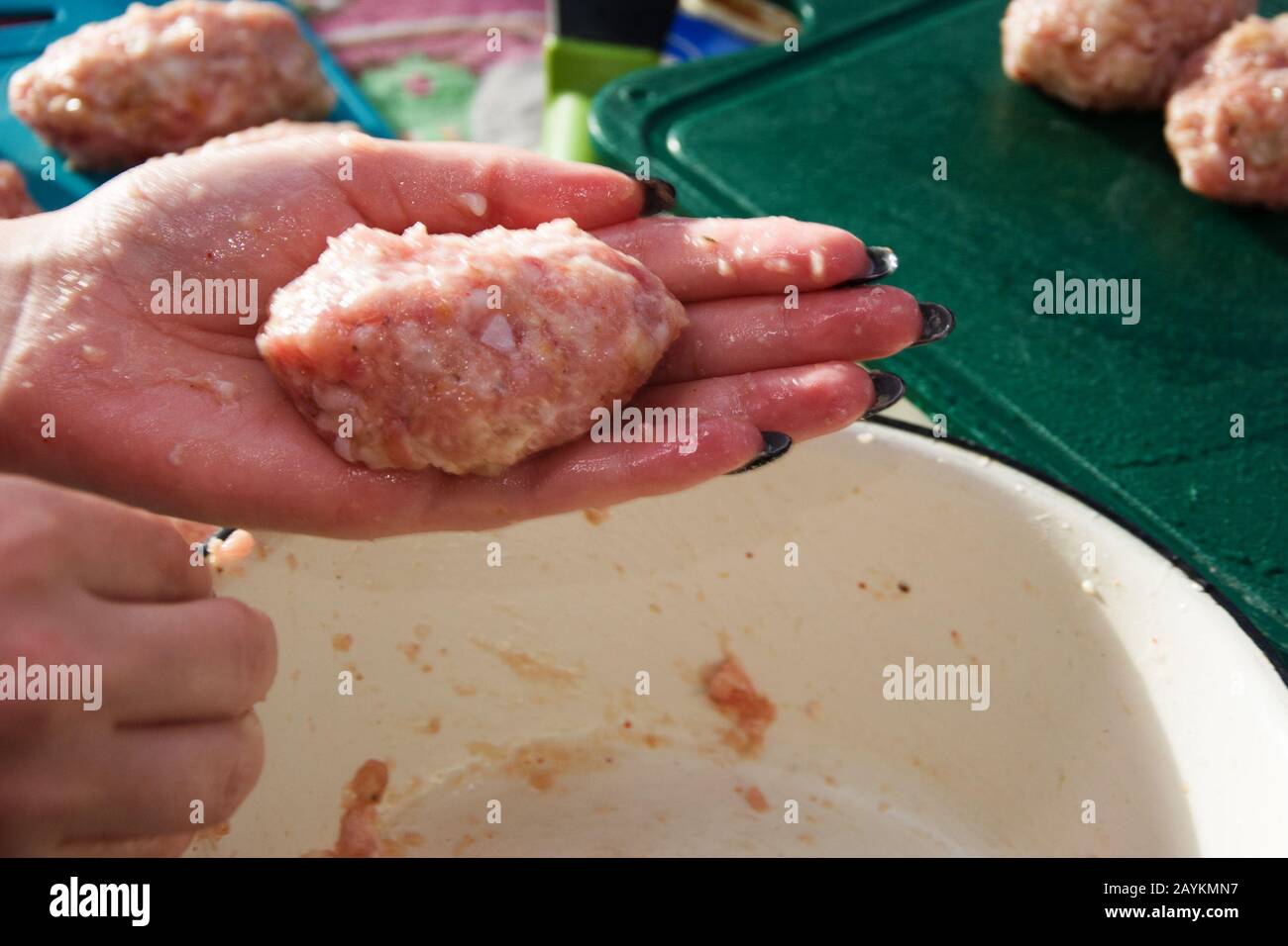 Una ragazza con una bella manicure nera fa tagli fatti in casa da carne macinata. Foto Stock