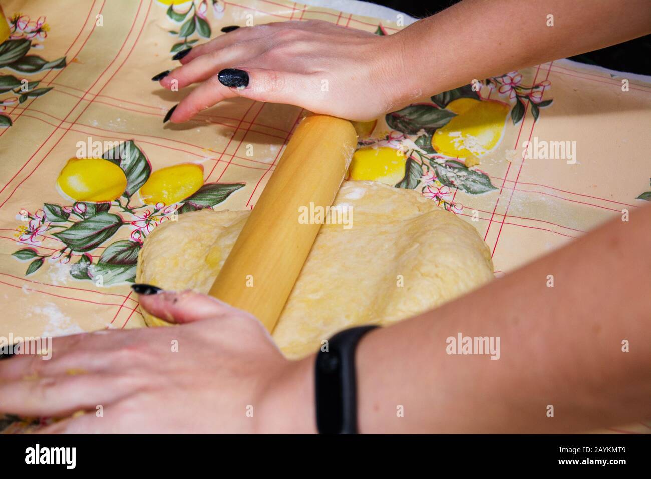 Una ragazza casalinga prepara l'impasto di farina, acqua e lievito per la base della pizza. Rotola con un perno di laminazione, rendendo lo strato di pasta sottile come poss Foto Stock