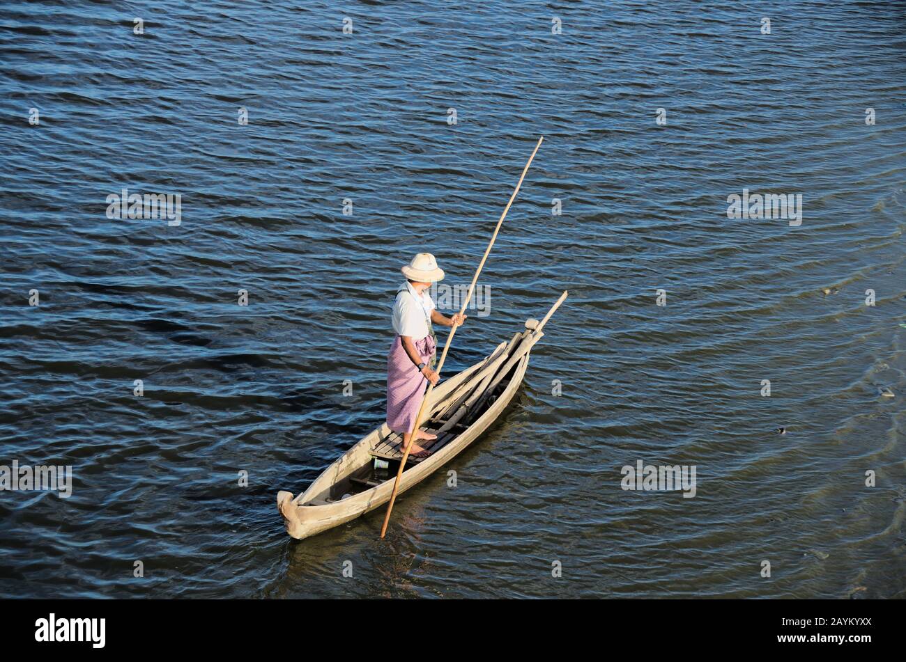 L'uomo ruggito una piccola barca di sampan al lago Taungthaman al ponte famoso U-bein. Mandalay, Myanmar. Foto Stock