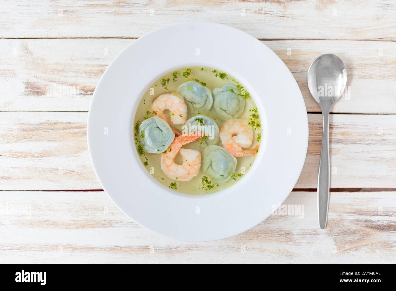Gnocchi di zuppa e gamberetti serviti con porri. Su vecchio sfondo bianco di legno. Foto Stock