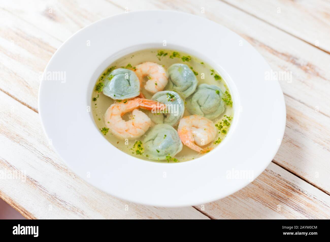 Gnocchi di zuppa e gamberetti serviti con porri. Su vecchio sfondo bianco di legno. Foto Stock