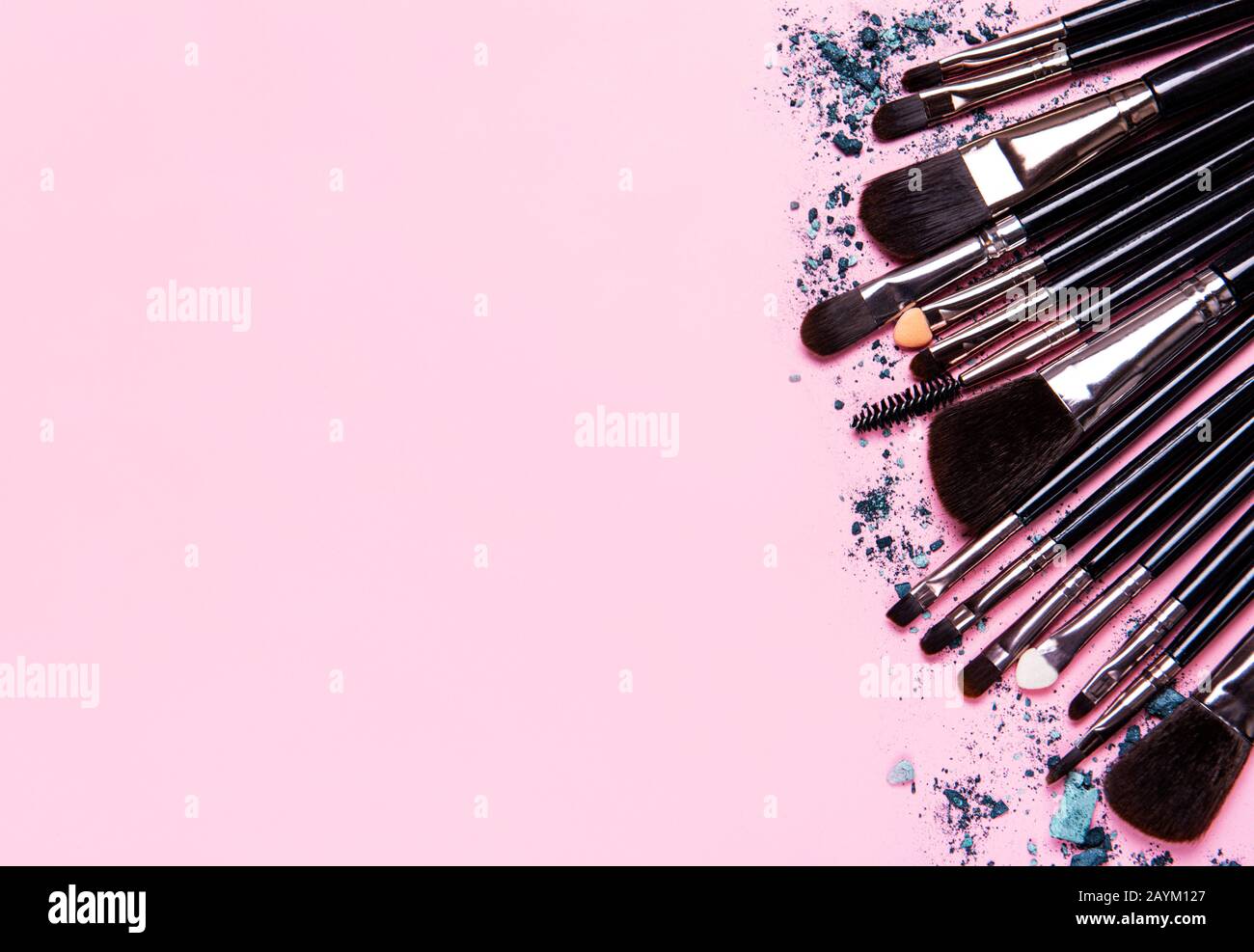 Diverse spazzole per il trucco e l'ombra degli occhi spezzata su sfondo rosa pastello. Disposizione piatta, vista dall'alto. Foto Stock