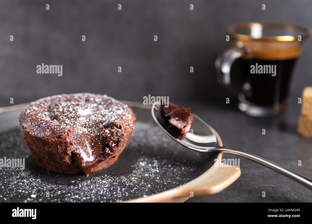 Torta di lava al cioccolato fatta in casa su un piatto nero con un caffè su sfondo nero Foto Stock