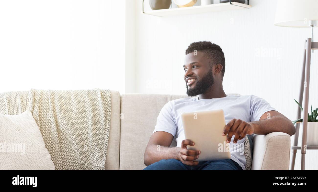 Allegro uomo africano che riposa a a casa con un tablet digitale Foto Stock