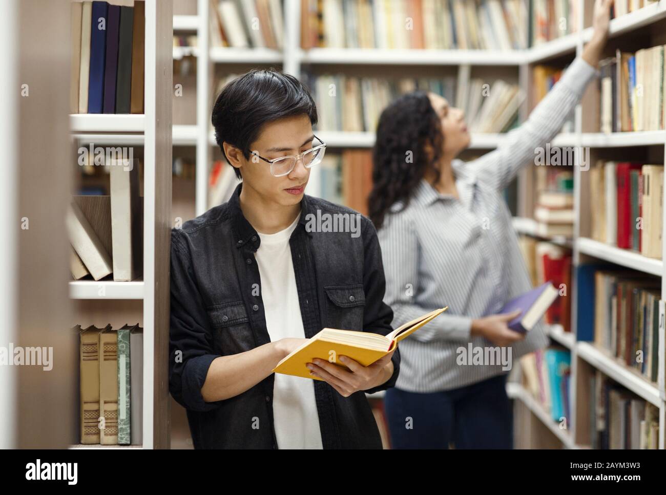 Libro di lettura del ragazzo giapponese messo a fuoco alla biblioteca Foto Stock