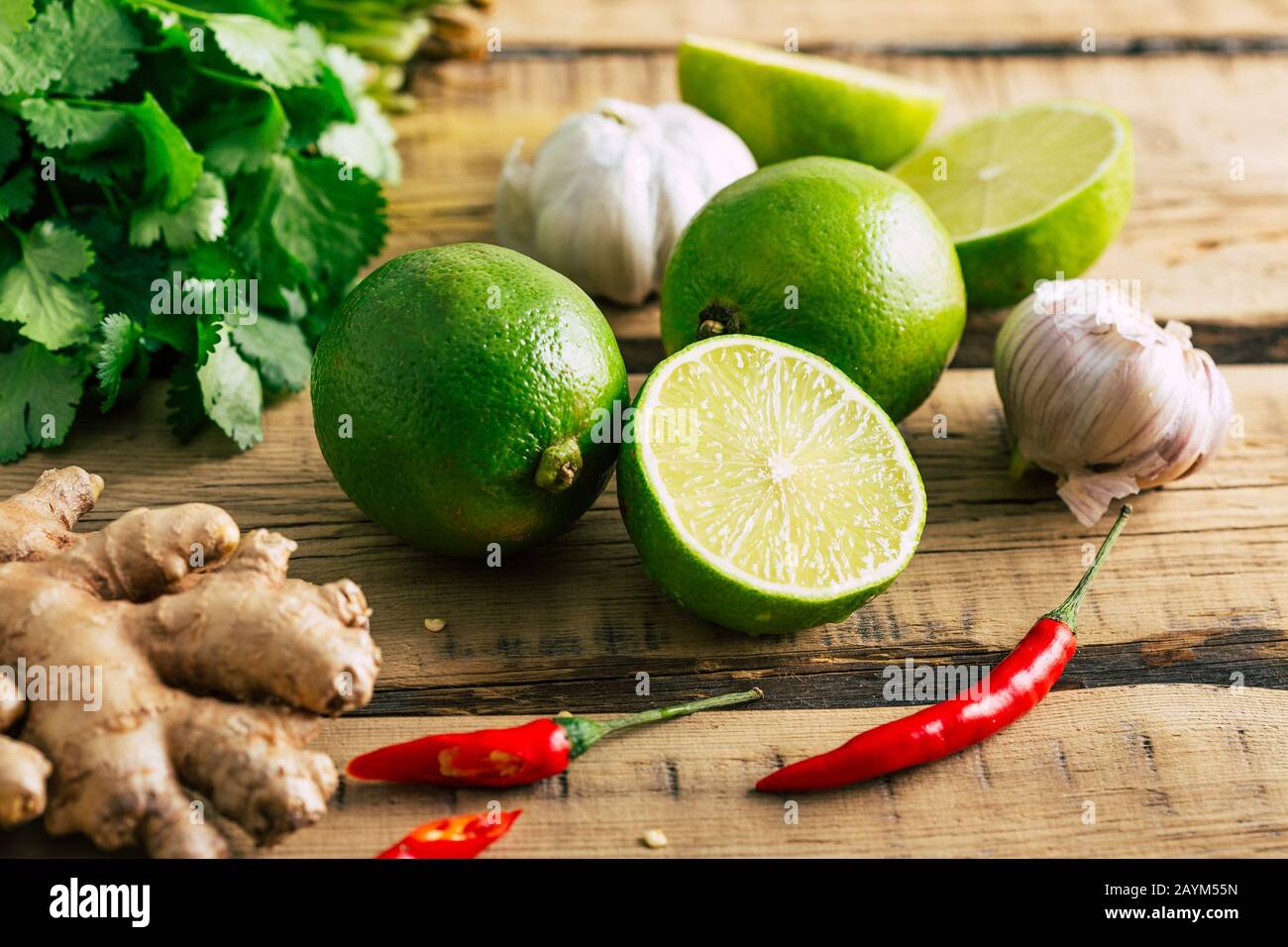 Cibo tailandese, lime, zenzero, peperoncino, aglio e coriandolo su sfondo di legno Foto Stock