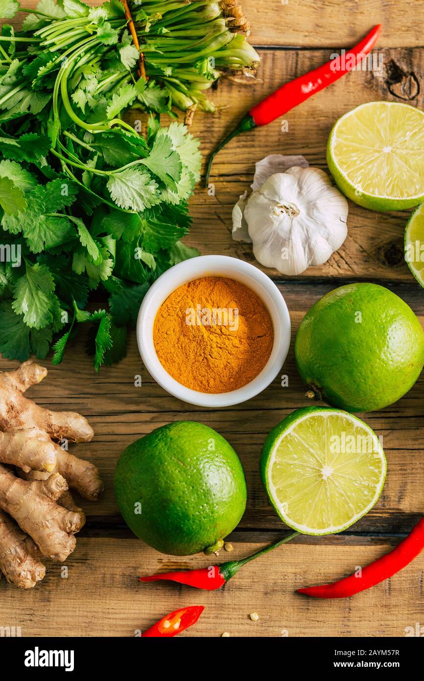 Cibo tailandese, lime, zenzero, peperoncino, aglio e coriandolo su sfondo di legno Foto Stock