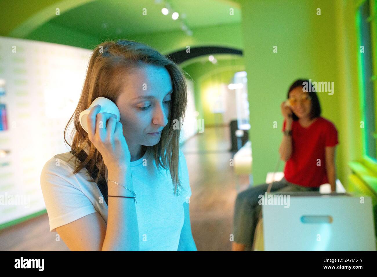 Donna che guarda la mostra del museo e ascolta l'audioguida utilizzando le cuffie nella galleria moderna. Concetto di istruzione e di svago Foto Stock