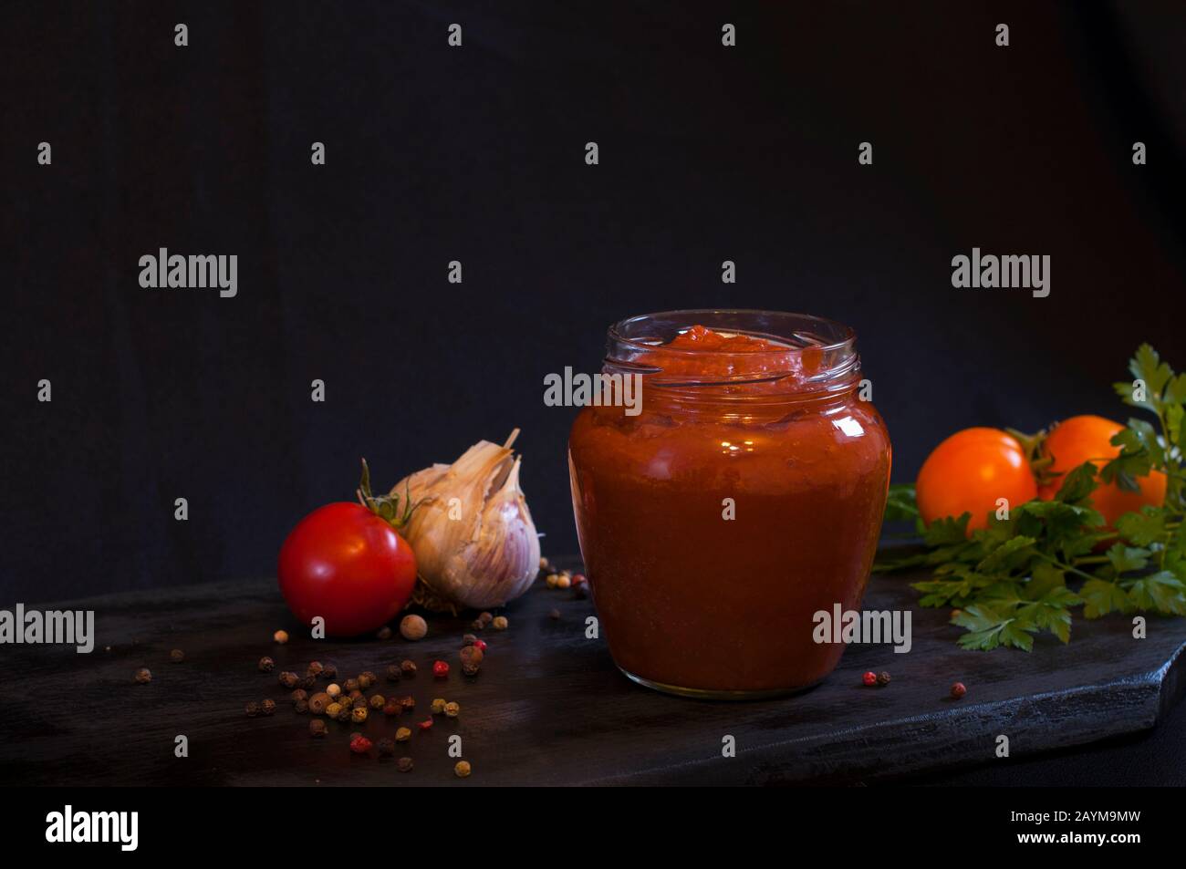 ketchup rosso fatto in casa in una composizione con pomodori maturi Foto Stock