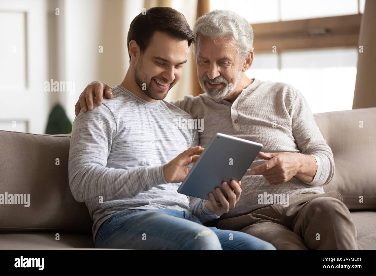 Grornup figlio che insegna a padre anziano maturo utilizzando applicazioni su tablet. Foto Stock