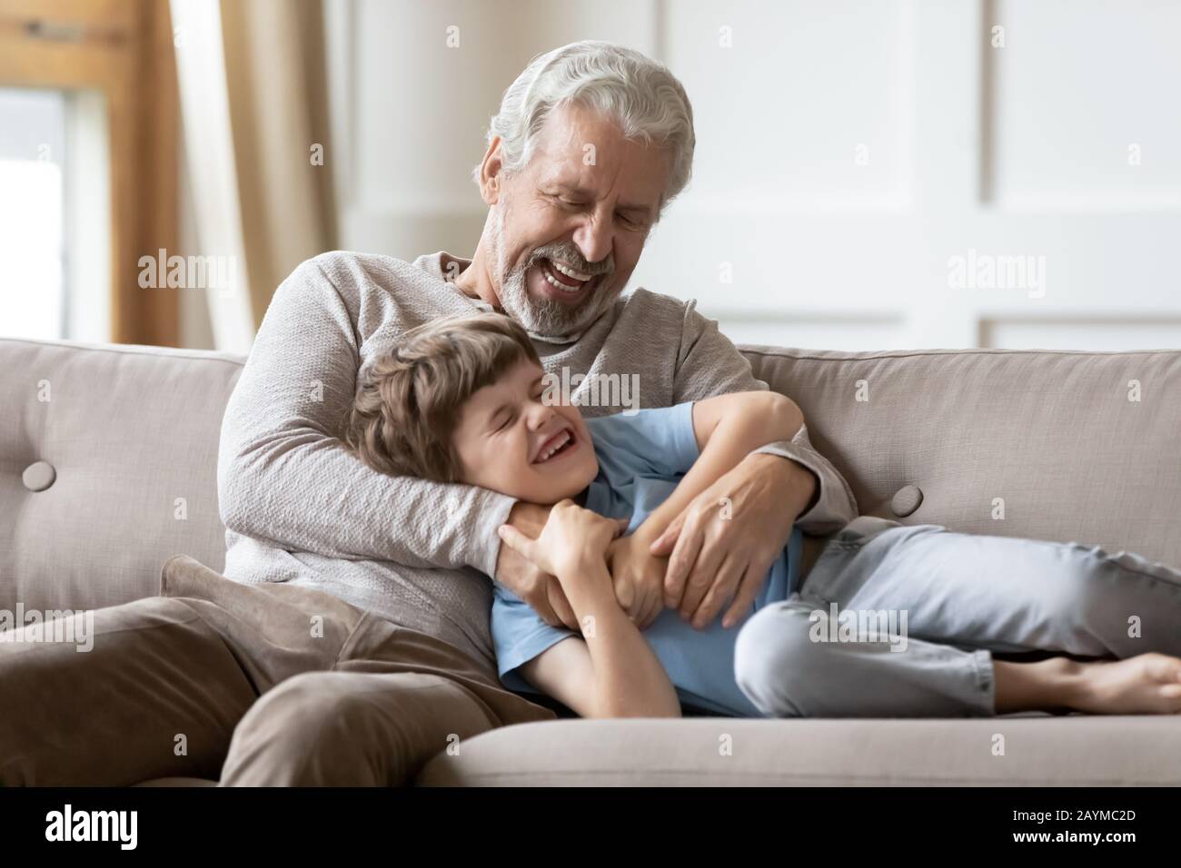 Il nonno anziano eccitato solletico ridendo il ragazzo del capretto. Foto Stock
