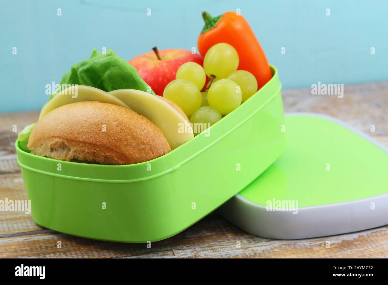 Pranzo a scuola con rotolo di formaggio, pepe giallo croccante e frutta fresca: Mela e uva Foto Stock