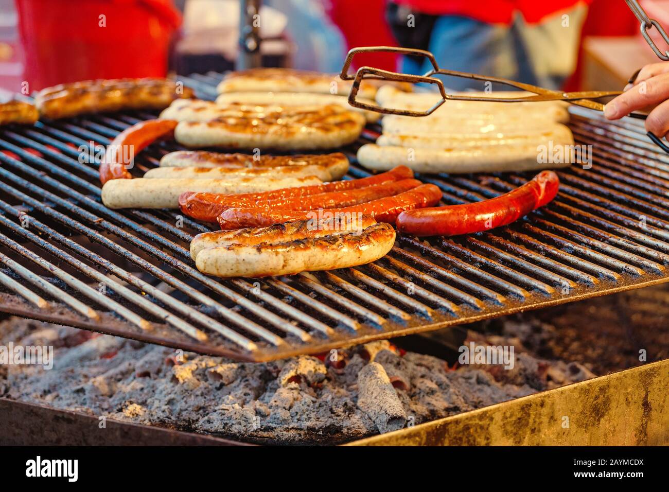 Uomo che cucina le salsicce su un grill piatto al mercato alimentare Street Foto Stock