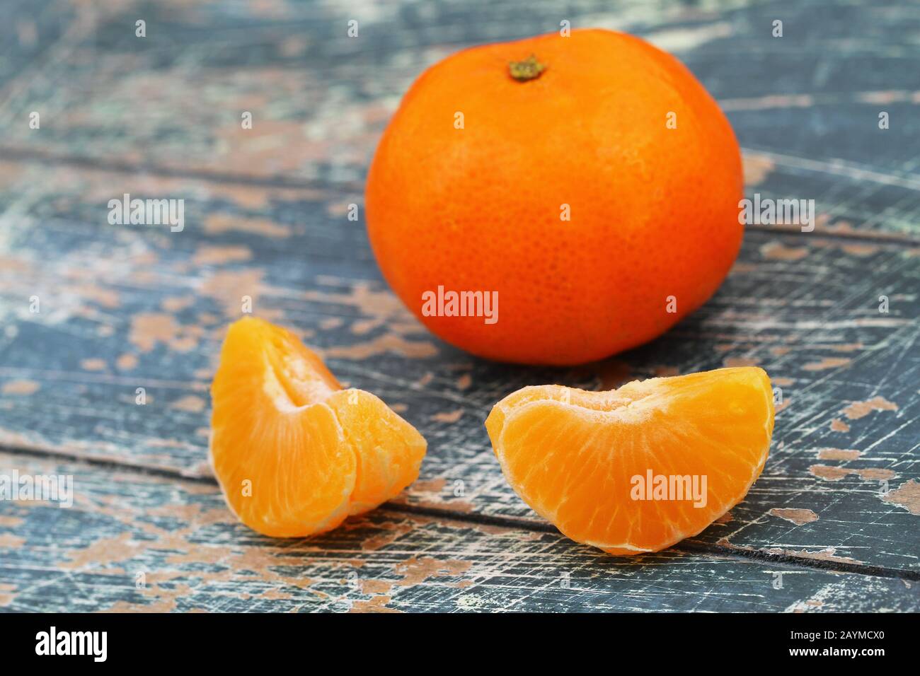 Pezzi di mandarino pelato e mandarino intero su una superficie rustica in legno Foto Stock