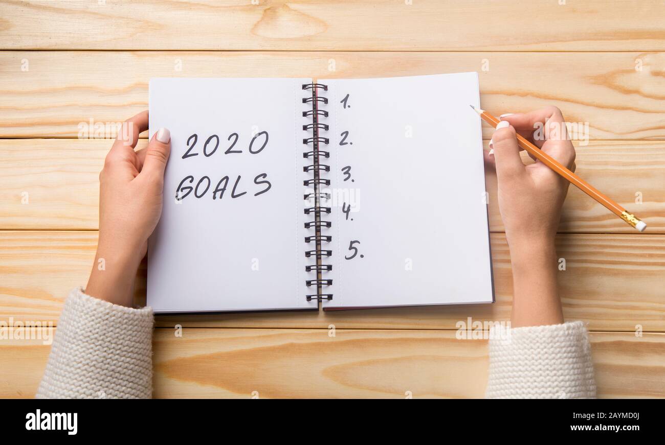 Pianificazione femminile 2020 obiettivi elenco in taccuino su tavola di legno Foto Stock