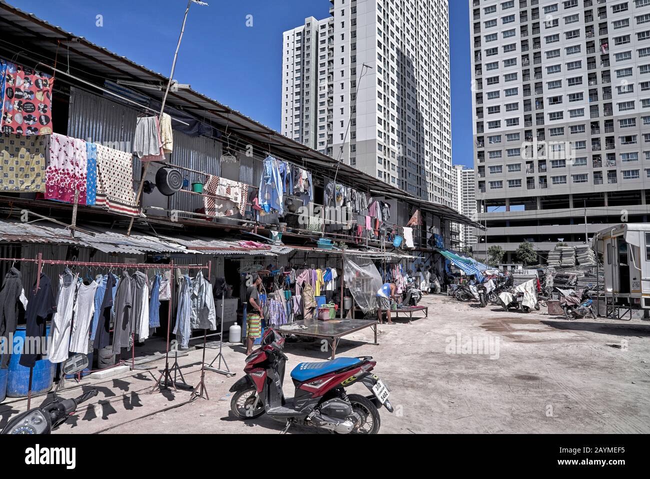 Alto e moderno condominio che contrasta con vecchio stile di stagno Shack economia alloggiamento dando il concetto di nuovo v vecchio. Thailandia Sud-Est Asiatico Foto Stock