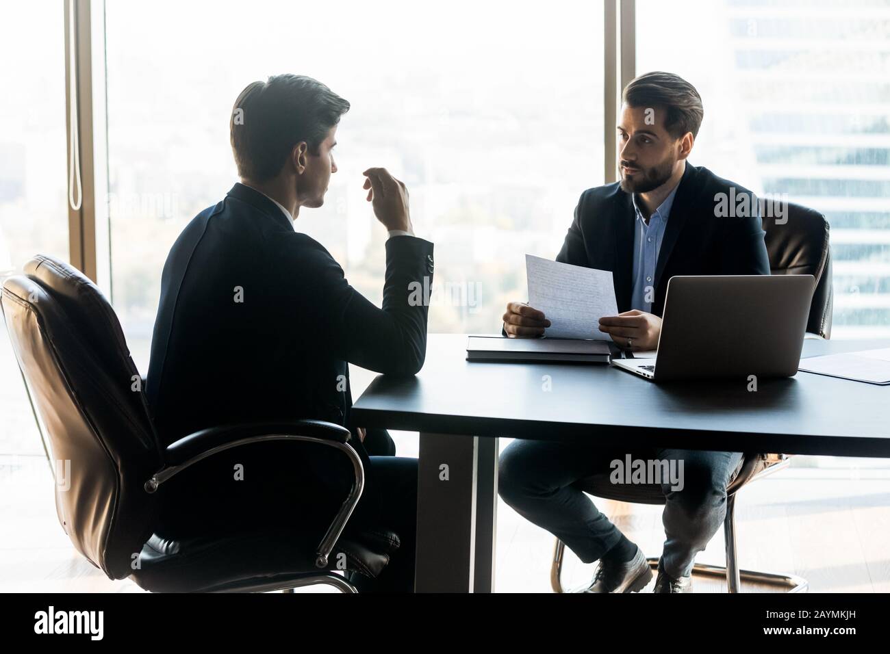 Un uomo d'affari serio che tiene un documento cv in ascolto di un nuovo candidato al lavoro. Foto Stock