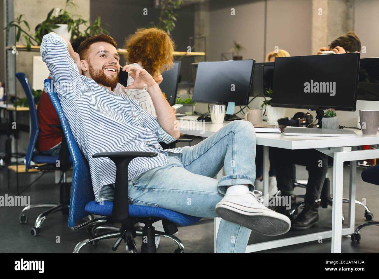 Giovane uomo rilassato che parla al telefono in un collega moderno Foto Stock