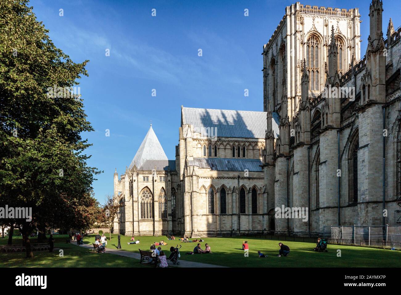 I visitatori seduti sull'erba fuori dal Minster di York in una giornata di sole in estate. York, Inghilterra, Regno Unito Foto Stock