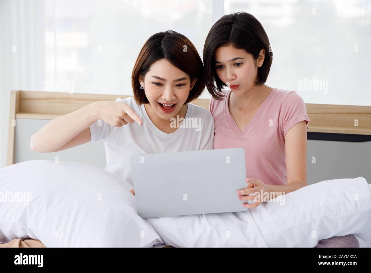 Due donne asiatiche è molto sorpresa mentre usano il loro portatile durante il surf il Internet. Concetto per attività adolescenti o amici, stile di vita a casa. Foto Stock