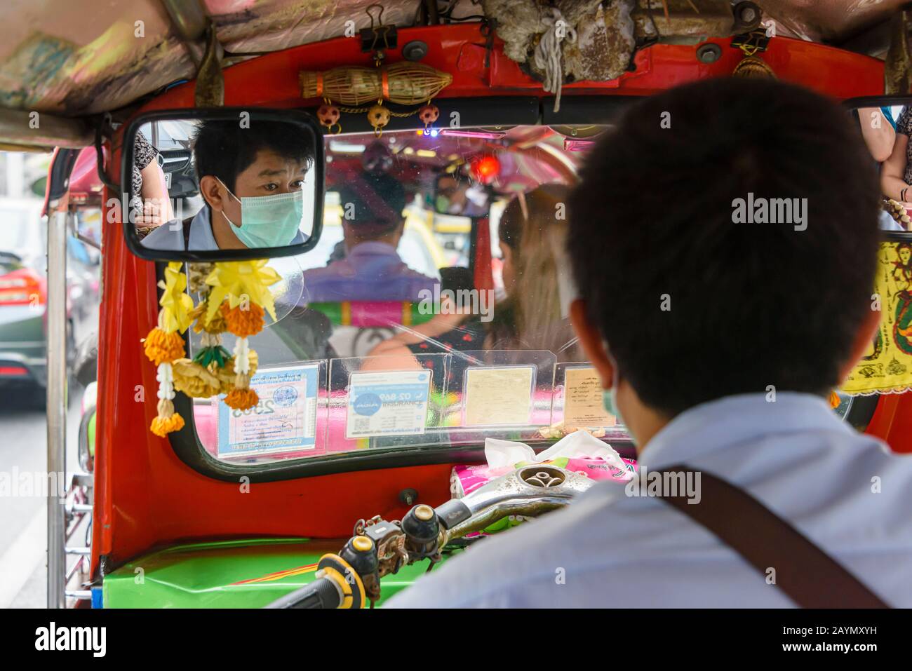 Un pilota tuk-tuk indossa una maschera facciale per proteggerlo contro Coronavirus COVID-19 SARS-COV-2 mentre guida per le strade di Bangkok, Thailandia. Foto Stock