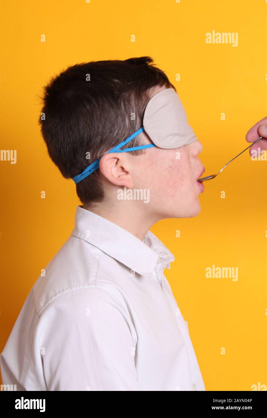 Prova del gusto alla cieca, ragazzo di 12 anni che degusta diversi alimenti bendati Foto Stock