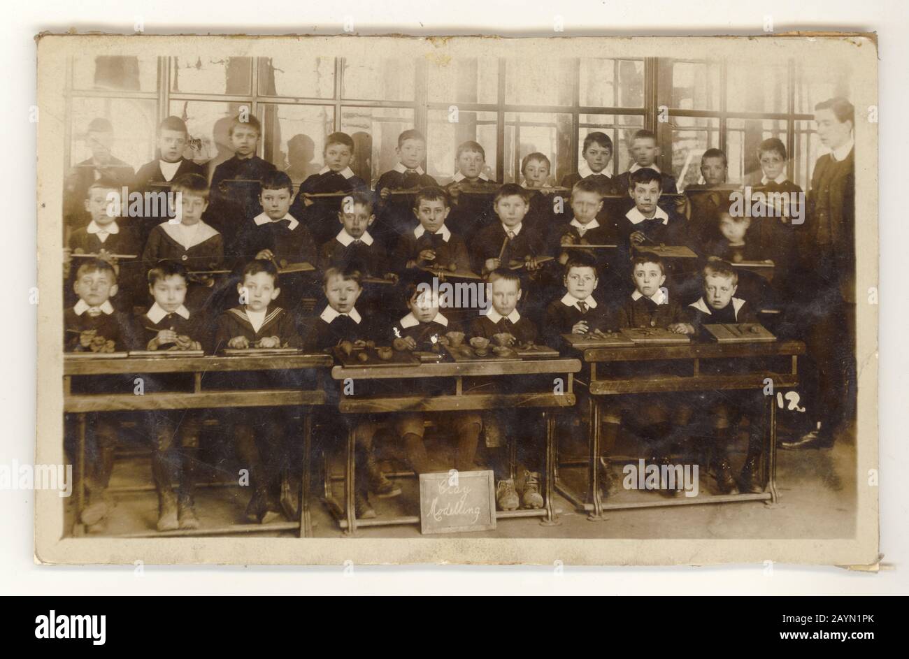 Cartolina edoardiana sbiadita di scolari in classe, seduta a file di scrivanie, modellazione argilla, al contrario è J.L. Maltby, Winchester, Hampshire, Inghilterra, U.K. circa 1905 Foto Stock