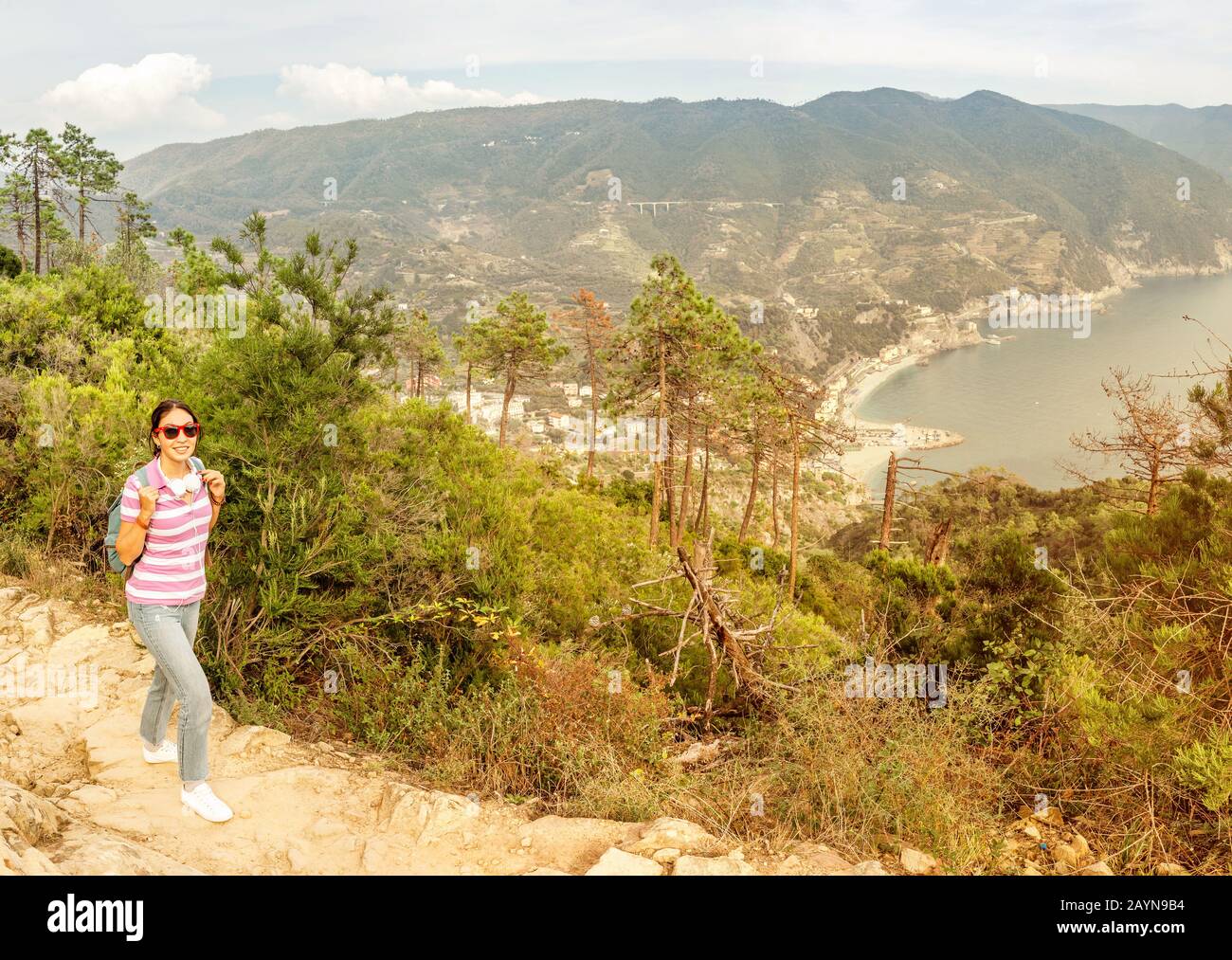 Felice giovane donna con zaino godendo bella stagione in Italia. Vacanze e viaggi nel parco nazionale di Cinqueterre, Mar mediterraneo. Foto Stock
