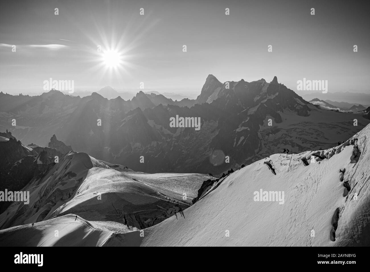 Una vista in bianco e nero del paesaggio degli escursionisti salendo sul Monte Bianco in una mattina soleggiata dalla stazione Aiguille du midi, Chamonix, Francia Foto Stock